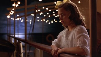 Movie still from “A Little Princess” (1995), directed by Alfonso Cuarón – A young girl in a white dress sitting on a railing at night; Close Up shot, Low angle