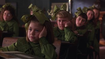 Movie still from “A Little Princess” (1995), directed by Alfonso Cuarón – A group of children sitting in a row wearing green bows; Close Up shot, Over the shoulder angle