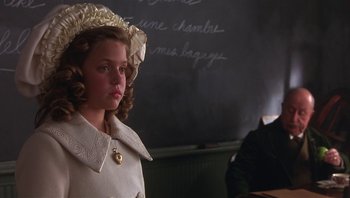 Movie still from “A Little Princess” (1995), directed by Alfonso Cuarón – A young girl in a white dress and a hat in front of a chalkboard; Close Up shot, Over the shoulder angle