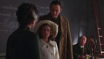 Movie still from “A Little Princess” (1995), directed by Alfonso Cuarón – A man and a woman standing next to a little girl; Medium shot, Over the shoulder angle