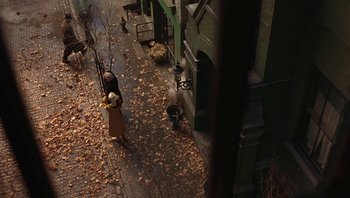 Movie still from “A Little Princess” (1995), directed by Alfonso Cuarón – A woman walking down the street in the rain; Extreme Wide shot, Overhead angle