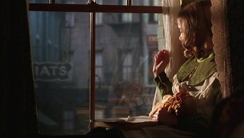 Movie still from “A Little Princess” (1995), directed by Alfonso Cuarón – A girl sitting on a window sill looking out a window; Medium shot, Over the shoulder angle
