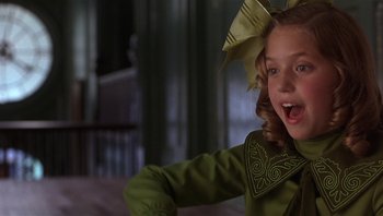Movie still from “A Little Princess” (1995), directed by Alfonso Cuarón – A young girl wearing a green dress with a bow on her head; Close Up shot, Over the shoulder angle