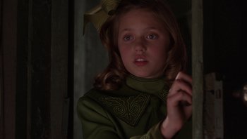 Movie still from “A Little Princess” (1995), directed by Alfonso Cuarón – A young girl in a green dress holding a pen; Close Up shot, Over the shoulder angle