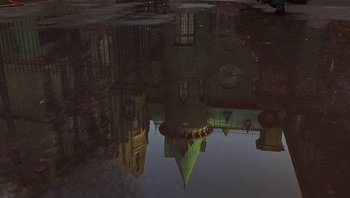 Movie still from “A Little Princess” (1995), directed by Alfonso Cuarón – A building reflected in a puddle of water on the ground; Wide shot, Low angle