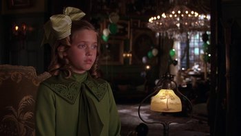 Movie still from “A Little Princess” (1995), directed by Alfonso Cuarón – A young girl in a green dress stands in front of a lamp; Close Up shot, Over the shoulder angle