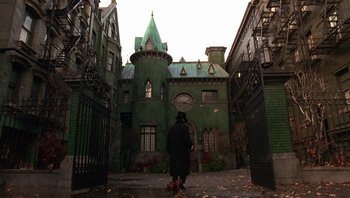 A person standing in front of an old green building