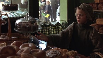 Movie still from “A Little Princess” (1995), directed by Alfonso Cuarón – A person sitting at a table with a plate of pastries; Medium shot, Over the shoulder angle