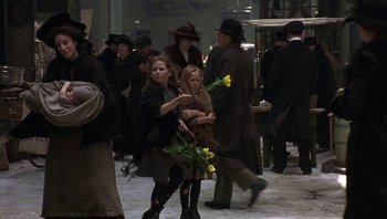 Movie still from “A Little Princess” (1995), directed by Alfonso Cuarón – A group of people walking in a crowd holding yellow flowers; Wide shot, Over the shoulder angle