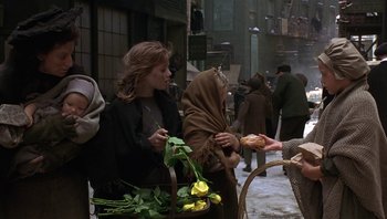 Movie still from “A Little Princess” (1995), directed by Alfonso Cuarón – A woman with a blanket around her neck and a basket of flowers in front of a woman; Medium shot, Over the shoulder angle