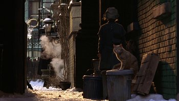 Movie still from “A Little Princess” (1995), directed by Alfonso Cuarón – A cat sitting on top of a trash can next to a building; Wide shot, High angle