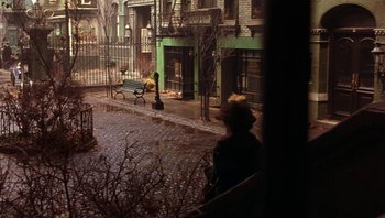 Movie still from “A Little Princess” (1995), directed by Alfonso Cuarón – Two people sitting on a bench on a sidewalk; Wide shot, High angle