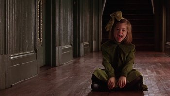 Movie still from “A Little Princess” (1995), directed by Alfonso Cuarón – A little girl sitting on the ground wearing a green outfit; Medium shot, High angle