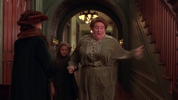 Movie still from “A Little Princess” (1995), directed by Alfonso Cuarón – An older woman in a green dress is in a hallway with two young girls; Medium shot, Low angle