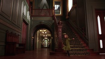 Movie still from “A Little Princess” (1995), directed by Alfonso Cuarón – A little girl standing on the bottom of a set of stairs; Wide shot, High angle
