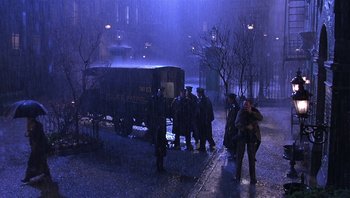 Movie still from “A Little Princess” (1995), directed by Alfonso Cuarón – A group of men standing in the rain next to a truck; Wide shot, High angle