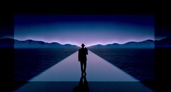 Movie still from “A Low Down Dirty Shame” (1994), directed by Keenen Ivory Wayans – A man in a hat is standing in front of a long path of light; Wide shot, Low angle