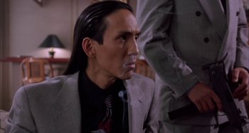 Movie still from “A Low Down Dirty Shame” (1994), directed by Keenen Ivory Wayans – A man in a suit smoking a cigarette in front of another man; Close Up shot, Over the shoulder angle