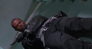 Movie still from “A Low Down Dirty Shame” (1994), directed by Keenen Ivory Wayans – A man laying on the ground wearing a black jacket; Medium shot, Overhead angle