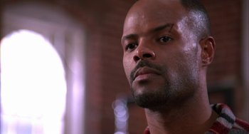 Movie still from “A Low Down Dirty Shame” (1994), directed by Keenen Ivory Wayans – A man's face in a room with a brick wall; Close Up shot, Low angle