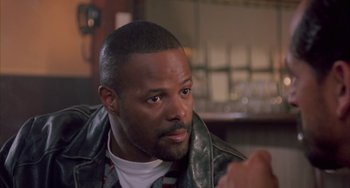 Movie still from “A Low Down Dirty Shame” (1994), directed by Keenen Ivory Wayans – A person sitting in a room; Close Up shot, Over the shoulder angle