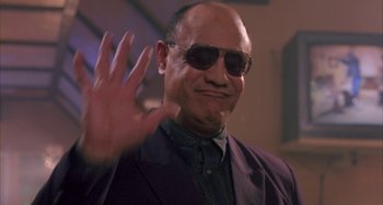 Movie still from “A Low Down Dirty Shame” (1994), directed by Keenen Ivory Wayans – A man in a suit and sunglasses waving; Medium shot, Low angle