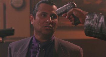 Movie still from “A Low Down Dirty Shame” (1994), directed by Keenen Ivory Wayans – A man in a purple suit holding a gun up to his head; Close Up shot, Over the shoulder angle