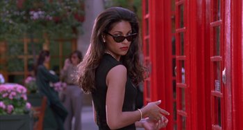 Movie still from “A Low Down Dirty Shame” (1994), directed by Keenen Ivory Wayans – A woman in a black dress standing in front of a red phone booth; Medium shot, Low angle