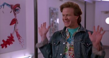 Movie still from “A Low Down Dirty Shame” (1994), directed by Keenen Ivory Wayans – A man in a jean jacket waving at the camera; Medium shot, Low angle