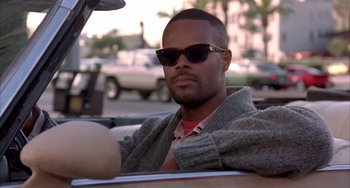 Movie still from “A Low Down Dirty Shame” (1994), directed by Keenen Ivory Wayans – A man sitting in the back seat of a car wearing sunglasses; Close Up shot, Low angle