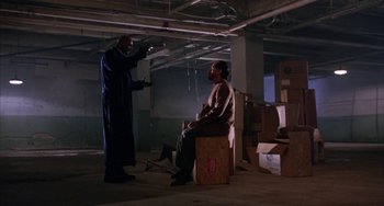 Movie still from “A Low Down Dirty Shame” (1994), directed by Keenen Ivory Wayans – Two men are sitting on boxes in an empty room; Wide shot, Low angle