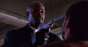 Movie still from “A Low Down Dirty Shame” (1994), directed by Keenen Ivory Wayans – A man holding a gun while wearing a tie; Close Up shot, Low angle