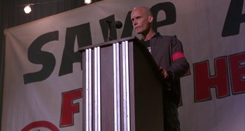 Movie still from “A Low Down Dirty Shame” (1994), directed by Keenen Ivory Wayans – A man standing at a podium speaking to a crowd; Medium shot, Low angle