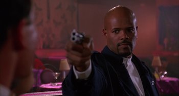 Movie still from “A Low Down Dirty Shame” (1994), directed by Keenen Ivory Wayans – A man holding a gun in his right hand; Close Up shot, Low angle