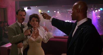 Movie still from “A Low Down Dirty Shame” (1994), directed by Keenen Ivory Wayans – A group of people standing around a room; Medium shot, Over the shoulder angle