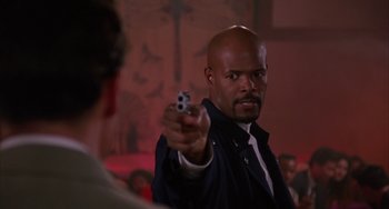 Movie still from “A Low Down Dirty Shame” (1994), directed by Keenen Ivory Wayans – A man holding a gun pointed at the camera; Close Up shot, Low angle