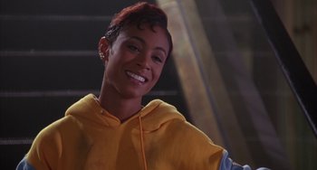 Movie still from “A Low Down Dirty Shame” (1994), directed by Keenen Ivory Wayans – A woman in a yellow hoodie smiling for the camera; Close Up shot, Low angle