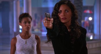 Movie still from “A Low Down Dirty Shame” (1994), directed by Keenen Ivory Wayans – A woman holding a cell phone in front of another woman; Medium shot, Over the shoulder angle