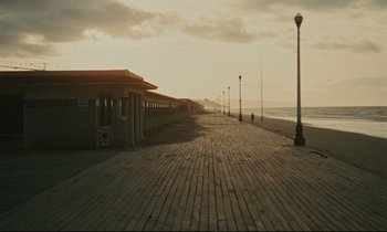 Movie still from “A Man and a Woman” (1966), directed by Claude Lelouch – The boardwalk is lined with lights on a cloudy day; Extreme Wide shot, High angle