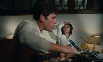 Movie still from “A Man and a Woman” (1966), directed by Claude Lelouch – A man and a woman sitting in front of a guitar; Medium shot, High angle