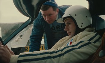 Movie still from “A Man and a Woman” (1966), directed by Claude Lelouch – A man standing next to another man in a car; Medium shot, Low angle