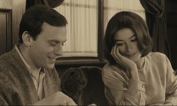 Movie still from “A Man and a Woman” (1966), directed by Claude Lelouch – A man and a woman sitting next to each other; Close Up shot, Over the shoulder angle