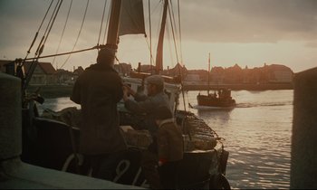Movie still from “A Man and a Woman” (1966), directed by Claude Lelouch – Two men on a boat in the water at sunset; Wide shot, Low angle