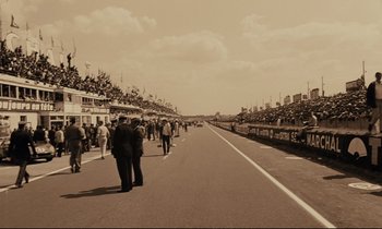 Movie still from “A Man and a Woman” (1966), directed by Claude Lelouch – A group of people standing on the side of a road; Extreme Wide shot, High angle