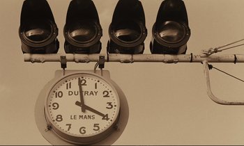 Movie still from “A Man and a Woman” (1966), directed by Claude Lelouch – A clock hanging on the side of a wall; Extreme Close Up shot, Low angle