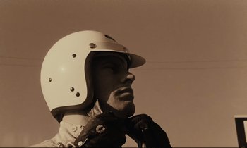 Movie still from “A Man and a Woman” (1966), directed by Claude Lelouch – A man wearing a motorcycle helmet and a leather jacket; Close Up shot, Low angle