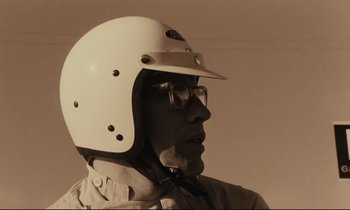 Movie still from “A Man and a Woman” (1966), directed by Claude Lelouch – An older man wearing a helmet and glasses; Close Up shot, Low angle