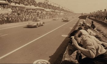 Movie still from “A Man and a Woman” (1966), directed by Claude Lelouch – A crowd of people watching a race on a race track; Wide shot, High angle