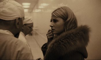 Movie still from “A Man and a Woman” (1966), directed by Claude Lelouch – A woman standing next to another woman in a room; Close Up shot, Over the shoulder angle
