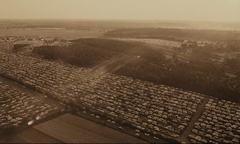 Movie still from “A Man and a Woman” (1966), directed by Claude Lelouch – An aerial view of a field of cars parked in a lot; Extreme Wide shot, High angle